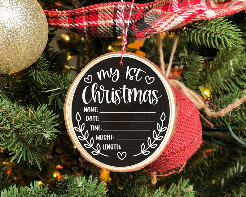 Pu&ograve; includere: Un ornamento natalizio in legno bianco e nero con il testo "My 1st Christmas" e righe vuote per nome, data, ora, peso e lunghezza.