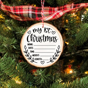 Pu&ograve; includere: Un ornamento rotondo in legno con il testo "♡ my 1st ♡ Christmas" e righe vuote per "Name", "Date", "Time", "Weight", e "Length".