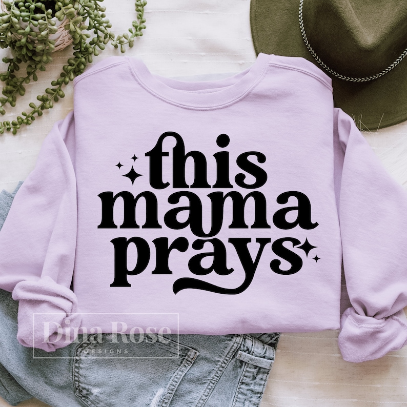 May include: A lavender sweatshirt with the text "this mama prays" in black lettering with a sparkle on either side of the text.