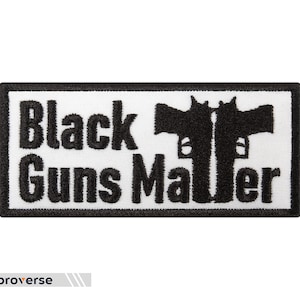 以下が含まれることがあります： 「Black Guns Matter」というテキストと、2 つの黒い拳銃のシルエットが刺繍された、黒と白の刺繍パッチです。
