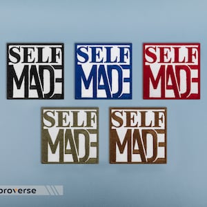 Puede incluir: Cinco parches bordados con el texto "SELF MADE" en letras blancas sobre una variedad de fondos de colores. Los colores son negro, azul, rojo, verde y marrón.