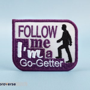 May include: Purple embroidered patch with white text that reads "Follow me I'm a Go-Getter" and a silhouette of a person walking up stairs.