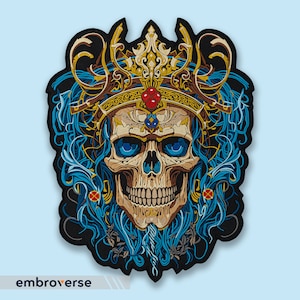 May include: Embroidered patch featuring a skull wearing a gold crown with blue and gold ornate details. The skull has blue eyes and a red jewel on its forehead.