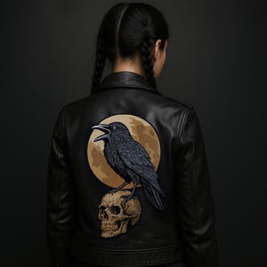 Può includere: Giacca in pelle nera con un design di corvo e teschio sul retro. Il corvo è appollaiato su un teschio, sullo sfondo di una luna piena. La giacca ha un classico stile biker con colletto e chiusura a zip. Il design è una toppa.