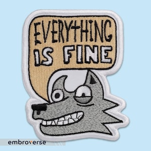 Puede incluir: Parche bordado con un lobo de dibujos animados con una expresión preocupada. El lobo es gris con detalles blancos y una nariz negra. Una burbuja de diálogo dice "EVERYTHING IS FINE" en texto negro sobre fondo beige.