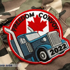 May include: An embroidered patch featuring a semi-truck, the Canadian flag, and the text "Freedom Convoy 2022". The patch is red, white, and blue.