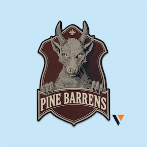 Könnte beinhalten: Ein schildförmiger Aufnäher mit einer detaillierten Illustration einer gehörnten Kreatur, deren Krallen auf einem Banner ruhen. Das Banner zeigt den Text PINE BARRENS in cremefarbener Schrift auf dunkelrotem Hintergrund.