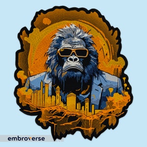 Puede incluir: Un parche bordado con un gorila que lleva gafas de sol y una chaqueta de traje, de pie frente a una ciudad. El fondo es una puesta de sol amarilla y naranja.
