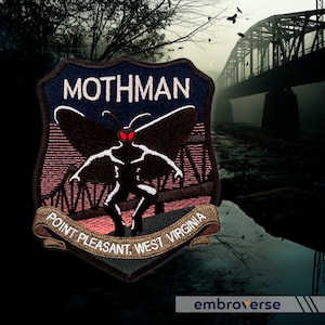 Op de afbeelding: Een zwart en bruin geborduurde patch met de tekst "MOTHMAN" in wit. De patch toont een gestileerde afbeelding van een mot-achtig wezen met rode ogen, staand op een brug. De tekst "POINT PLEASANT, WEST VIRGINIA" staat in een banner onder het wezen.