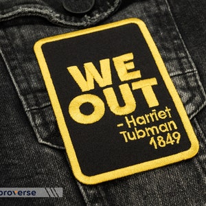 Peut inclure: Écusson brodé noir et jaune avec le texte "WE OUT - Harriet Tubman 1849".