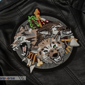 Puede incluir: Una chaqueta de cuero negra con un parche bordado que presenta tres cabezas de lobo con dientes afilados y hojas verdes. El parche es circular y tiene un fondo negro con un patrón gris y blanco.