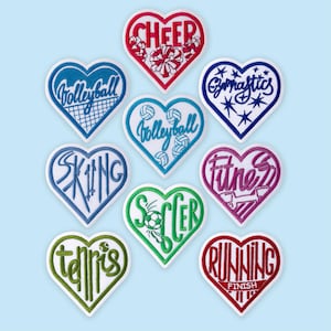 May include: A collection of heart-shaped embroidered patches featuring various sports and activities. Each patch has a white border and a different color, with words like "Cheer," "Volleyball," "Gymnastics," "Skiing," "Soccer," "Fitness," "Tennis," and "Running."