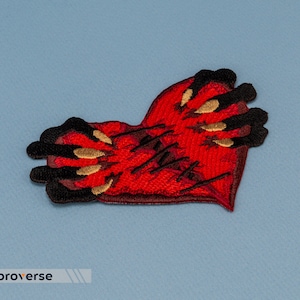May include: Red embroidered heart patch with black and gold stitching, depicting a hand with claws gripping the heart.