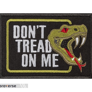 Può includere: Toppa ricamata con la scritta "DON'T TREAD ON ME" in bianco su sfondo nero, incorniciata da un bordo giallo. Un serpente verde con la lingua rossa è sul lato destro.