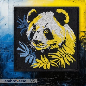 Pode incluir: Etiqueta bordada com um urso panda amarelo e branco com olhos e nariz pretos, rodeado de folhas azuis e amarelas sobre um fundo preto.