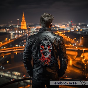 May include: A black leather jacket with a skull embroidered on the back. The skull is surrounded by flames and has red eyes. The jacket is worn by a person standing on a rooftop overlooking a city at night.