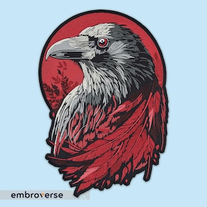 Puede incluir: Parche bordado de un cuervo con plumas rojas sobre un fondo rojo. El cuervo tiene un cuerpo negro con plumas grises y ojos rojos.