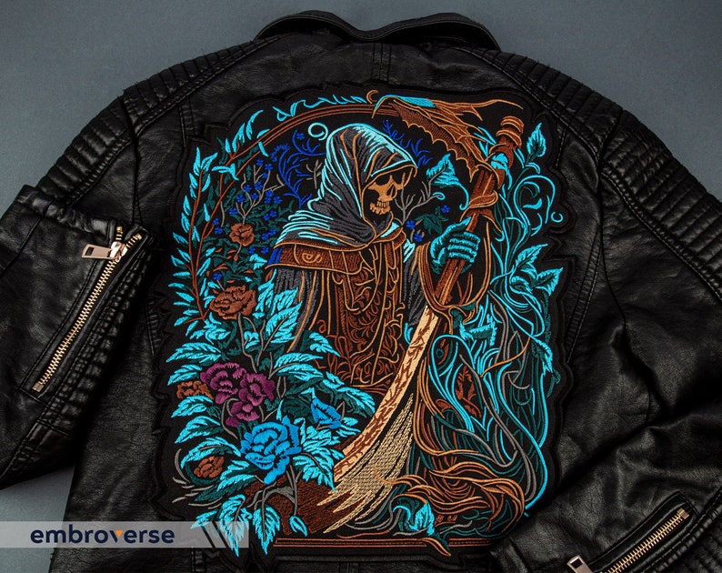 Puede incluir: Chaqueta de cuero negro con un parche bordado que representa una figura esquel&eacute;tica con una t&uacute;nica con capucha que sostiene una guada&ntilde;a, rodeada de dise&ntilde;os florales en tonos azules, verdes y marrones.