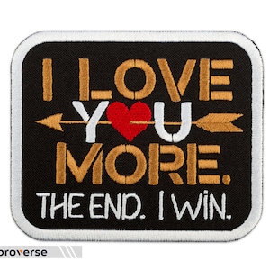 May include: A black and gold embroidered patch with the text "I LOVE YOU MORE. THE END. I WIN."