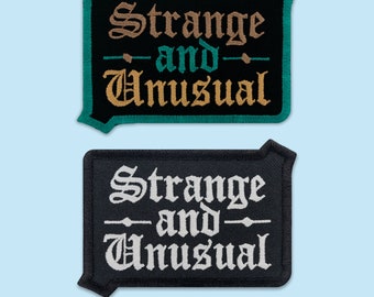May include: Two black embroidered patches with white stitching. The top patch has the text "Strange and Unusual" in gold and green thread. The bottom patch has the text "Strange and Unusual" in white thread.