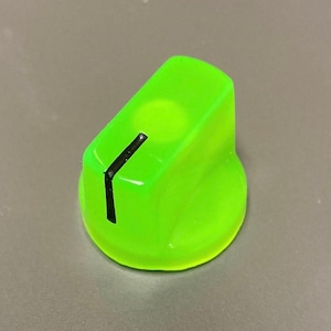 May include: A bright neon green control knob with a smooth, rounded base and a tapered top. A single, bold black vertical line is printed on the side to indicate position, extending from the top edge down toward the circular base of the component.