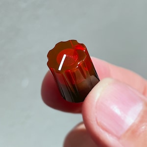 Op de afbeelding: Een rode en bruine plastic knop met een witte lijn in het midden. De knop wordt gebruikt om het volume of andere instellingen op elektronische apparaten aan te passen.