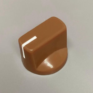 May include: A brown plastic control knob with a smooth, rounded cylindrical base and a flat top surface. A single, thin white indicator line is printed vertically along the side and extends onto the top edge of the knob for precise adjustment.