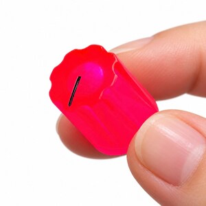 Op de afbeelding: Een fel neonroze cilindrische bedieningsknop met een geschulpte rand en een enkele zwarte indicatorlijn op het bovenoppervlak. De knop heeft een doorschijnende afwerking en verticale ribbels aan de zijkant voor grip.