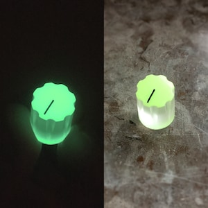 Può includere: Una manopola verde con una linea nera su di essa. La manopola brilla al buio.