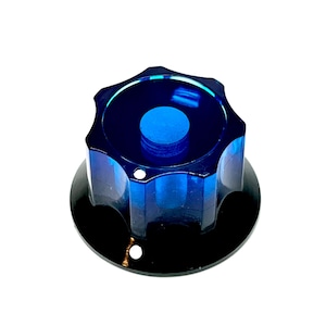 Könnte beinhalten: Ein blau-schwarzer Knopf mit sternförmiger Oberseite und kreisförmiger Basis. Der Knopf hat eine durchscheinende blaue Mitte und eine solide schwarze Basis mit zwei kleinen Löchern.