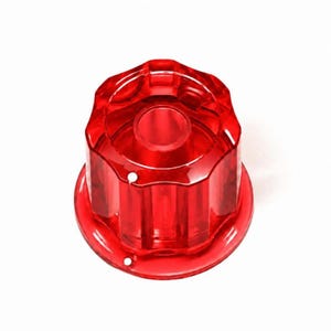 May include: A translucent red plastic faucet handle featuring a fluted, multi-sided cylindrical design with a circular top opening. The base is circular and flat, and the exterior surface has vertical ridges that provide a textured grip.