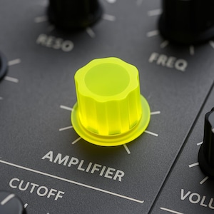 Könnte beinhalten: Nahaufnahme eines gelben Knopfes mit der Aufschrift "AMPLIFIER" auf einem schwarzen Synthesizer-Panel. Der Knopf ist von anderen Knöpfen mit den Aufschriften "CUTOFF", "FREQ" und "RESO" umgeben.
