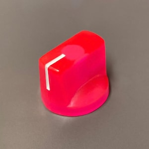 May include: A bright neon pink control knob with a smooth, cylindrical base and a flat top surface. A single, thin white indicator line is printed on the top and extends down the side of the knob to show the current setting or position clearly.