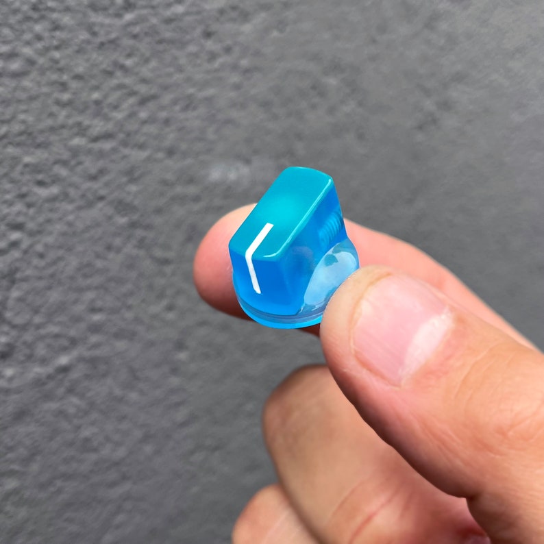 Puede incluir: Un mando de pl&aacute;stico azul claro con una l&iacute;nea blanca. El mando est&aacute; siendo sujetado por una mano.