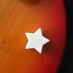 Peut inclure: Un bouton en forme d'étoile blanche sur un fond rouge et orange.