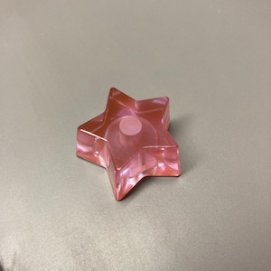 Op de afbeelding: Een roze glazen flessenstop in de vorm van een ster.