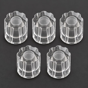 May include: A set of five clear, cylindrical knobs with a fluted, scalloped edge design. Each knob features a smooth, transparent exterior shell and a central, frosted circular insert, providing a clean and uniform appearance for hardware applications.