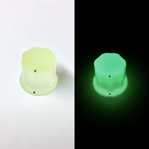 May include: A pale yellow, octagonal-shaped knob with two black dots. The knob glows green in the dark.