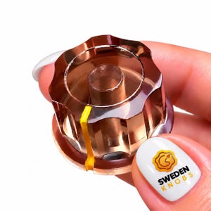 May include: A translucent, amber-colored, fluted control knob featuring a prominent vertical yellow indicator line. The knob has a cylindrical center post and a scalloped outer edge, designed for adjustment on electronic equipment.