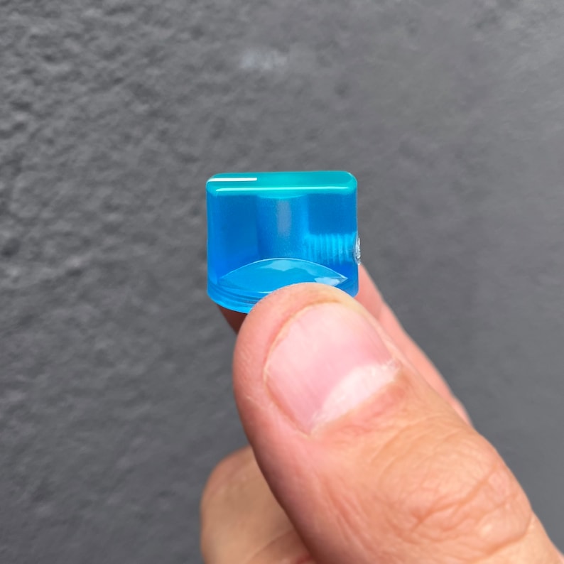 Puede incluir: Una perilla de pl&aacute;stico azul claro con un peque&ntilde;o agujero en el centro.