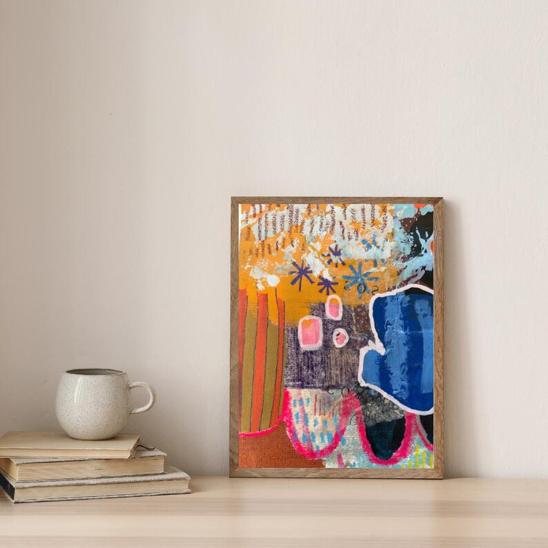 May include: A rectangular framed abstract painting featuring a vibrant composition of orange, blue, and pink shapes. The artwork includes vertical stripes, star-like marks, and a large, irregular blue form outlined in white, all set within a wooden frame.