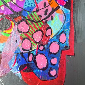 May include: Abstract painting with a colourful, geometric design. The painting features a variety of shapes and colours, including pink, blue, green, red, and black. The painting is on a dark grey background.