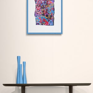 Peut inclure: Une peinture abstraite encadr&eacute;e avec un design color&eacute; et textur&eacute;. La peinture est dans un cadre bleu et est accroch&eacute;e &agrave; un mur blanc. Trois vases bleus sont sur une table noire devant la peinture.