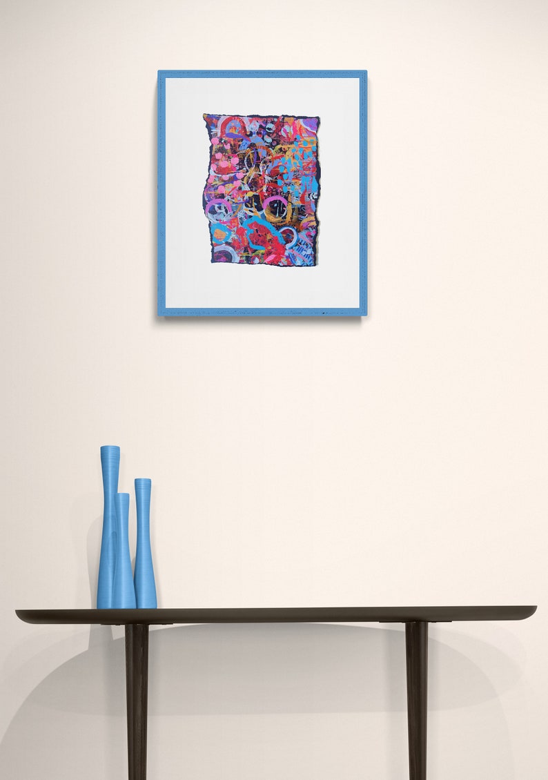 Peut inclure: Une peinture abstraite encadr&eacute;e avec un design color&eacute; et textur&eacute;. La peinture est dans un cadre bleu et est accroch&eacute;e &agrave; un mur blanc. Trois vases bleus sont sur une table noire devant la peinture.