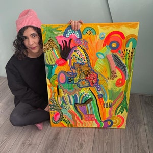 May include: A colorful abstract painting with a yellow background and bright green, pink, blue, and orange shapes. The painting is framed and has a textured surface.