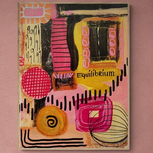 May include: Abstract painting with a pink, yellow, and black color scheme. The painting features geometric shapes, lines, and circles. The word "Equilibrium" is written in black paint on the canvas.