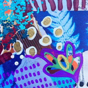 K&ouml;nnte beinhalten: Abstrakte Mixed-Media-Kunst mit einer lebendigen Farbpalette. Die Komposition zeigt blaue, violette und orange Farbt&ouml;ne, akzentuiert mit Blattgold und t&uuml;rkisblauem Glitzer. Das Kunstwerk hat ein strukturiertes Aussehen mit verschiedenen Formen und Mustern.