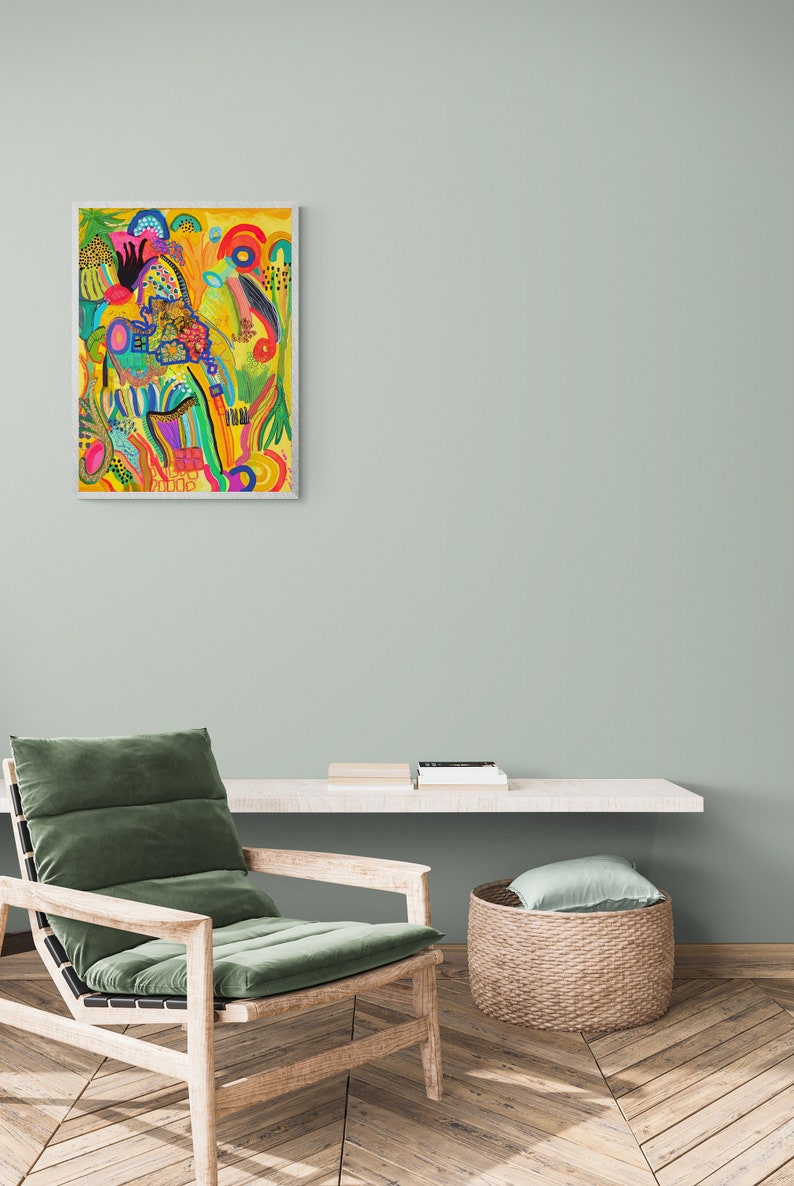 May include: A colorful abstract painting with a yellow background and a variety of shapes and colors, including red, orange, yellow, green, blue, and purple. The painting is framed in a white frame and is hanging on a light green wall.