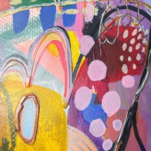Puede incluir: Pintura abstracta con colores y formas audaces. La pintura presenta un fondo amarillo, naranja y rosa con un dibujo de l&iacute;nea negro y plateado. Tambi&eacute;n hay c&iacute;rculos rosas y azules en toda la pintura.
