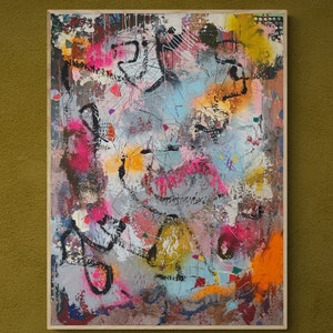 Op de afbeelding: Abstract schilderij op canvas met een mix van kleuren, waaronder roze, blauw, geel, zwart en wit. Het schilderij heeft een textuur en lijkt te zijn gemaakt met meerdere lagen verf.